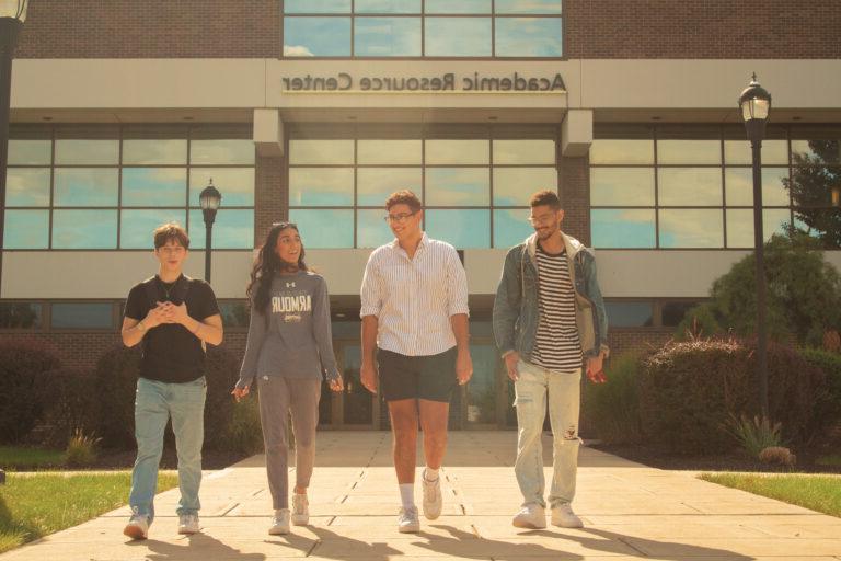Image shows four students walking in front of the Academic Resource Center.